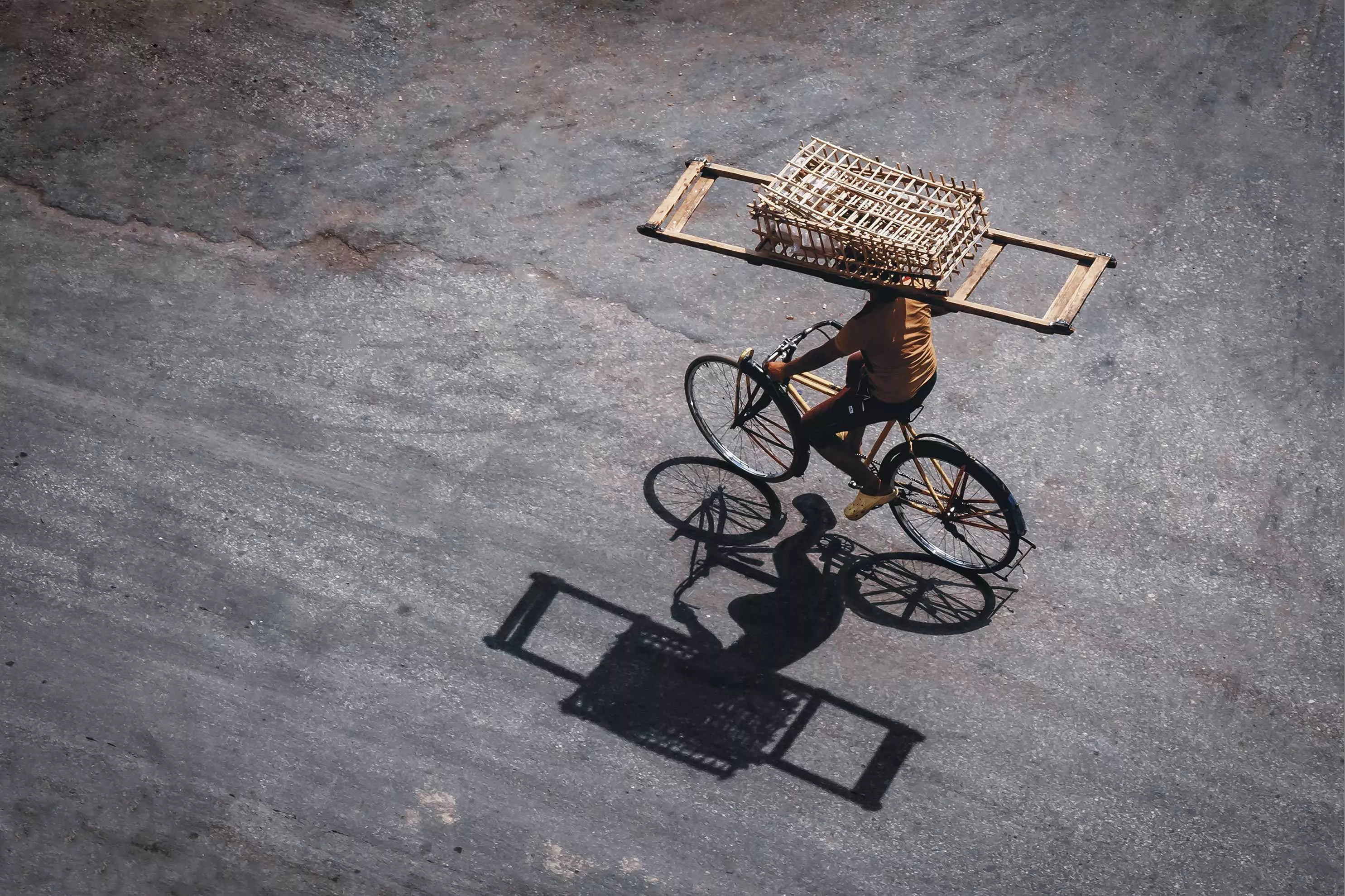 Perfect Balance – A Man on a Bicycle Carrying a Wooden Basket from a Top-Down View